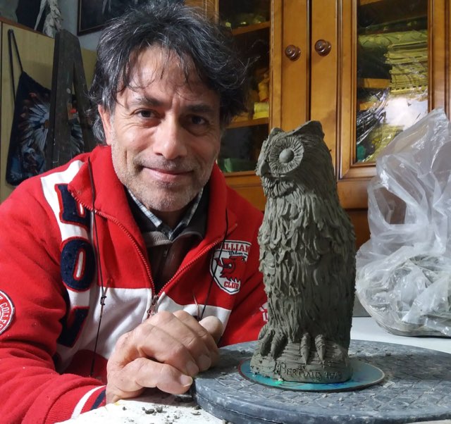 Maurizio Bertino al lavoro su un gufo in terracotta.