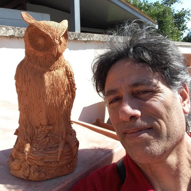 Maurizio Bertino accanto a un gufo in terracotta, 2019.